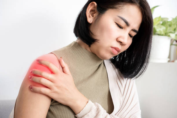 A woman is holding her shoulder and appears to be in pain.